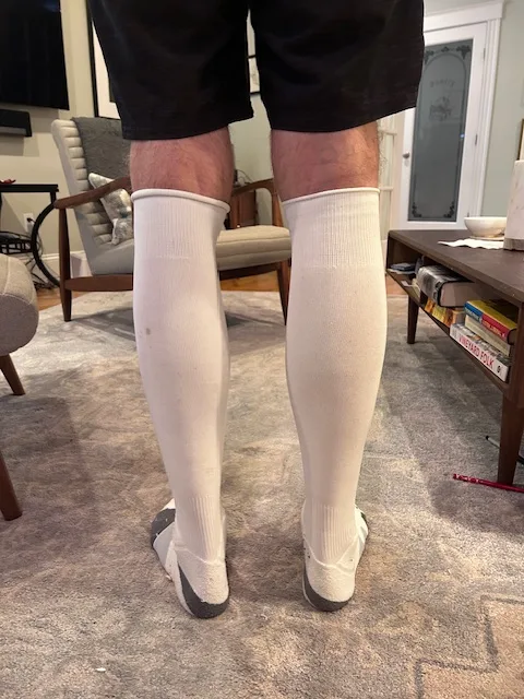 Author's legs wearing white knee-high compression socks in a living room