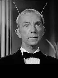Black-and-white photo of a man in a tuxedo with two thin antennae rising from his head